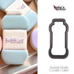 May include: A light blue and white cookie decorated to resemble a bubble bottle, with the word "Bubbles" in purple icing. The cookie is next to a cookie cutter in the shape of a bubble bottle. The cookie cutter is black and has the text "Bubble Bottle Cookie Cutter".