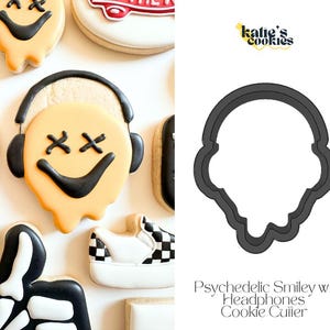 May include: Cookies decorated with a psychedelic smiley face wearing headphones. The smiley face has black eyes and a black smile. Other cookies in the image include a skateboard, a shoe, and a skeleton hand. The cookie cutter is also shown.