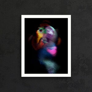 May include: A rectangular framed wall art piece featuring an abstract, motion-blurred composition. The image displays vibrant streaks of red, yellow, blue, and a prominent bright pink heart-shaped form set against a deep black background.