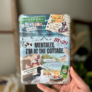 May include: A clear phone case decorated with a collage design. The design includes the word "MONTREAL", hockey-related images, and the phrase "MENTALLY, I'M AT THE COTTAGE." Other elements include a loon, a campfire, and a can of Canada Dry.