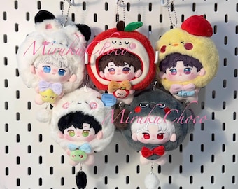 May include: A collection of plush doll keychains, each featuring a character in a different animal or fruit-themed costume. The keychains include a bunny, apple, chick, panda, and a gray creature. Each doll has a chain for easy attachment.