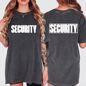 May include: Dark gray t-shirt with the word "SECURITY" printed in large white block letters on the front and back. The shirt has a slightly faded, vintage look.