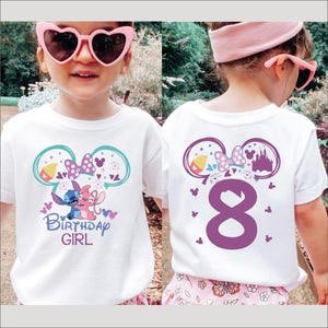 A young girl wearing a white t-shirt with a Disney-themed design, including Mickey Mouse ears and the text "Birthday Girl". She is also wearing pink heart-shaped sunglasses and a pink headband.