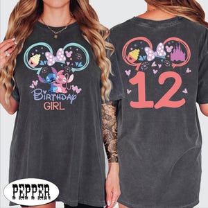 A woman wearing a gray t-shirt with a Disney-themed design and the text "Birthday Girl" printed on it.