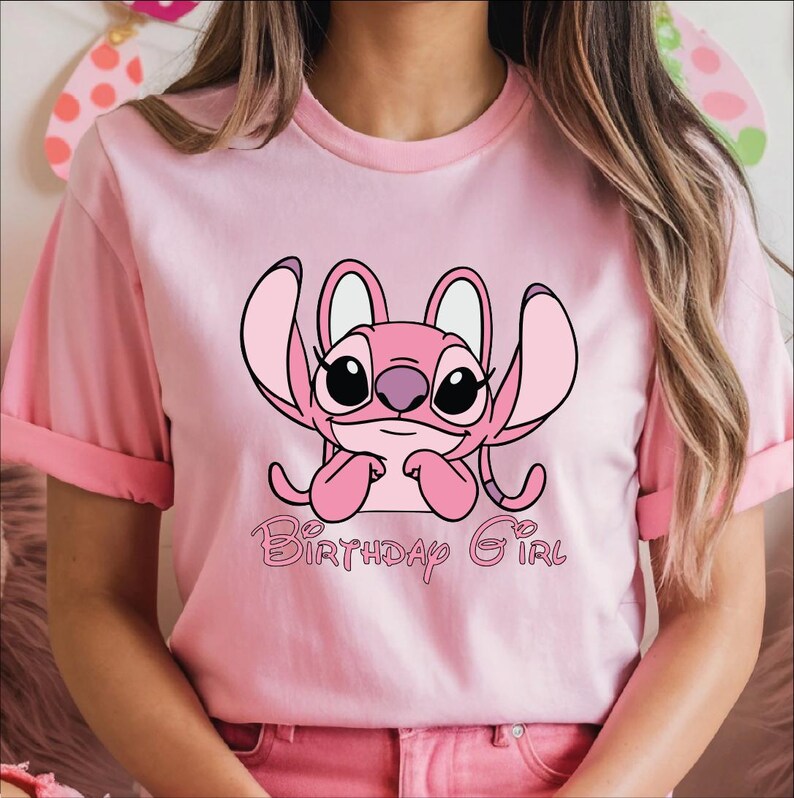 A woman wearing a pink t-shirt with a cartoon character and the text "Birthday Girl" printed on it.