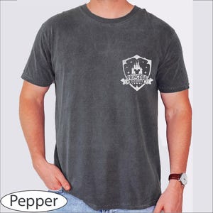 May include: Pepper-colored t-shirt with a crew neck and short sleeves. The shirt features a white graphic on the chest that reads "Princess Security" with a castle design. The shirt is made of a soft, comfortable material.