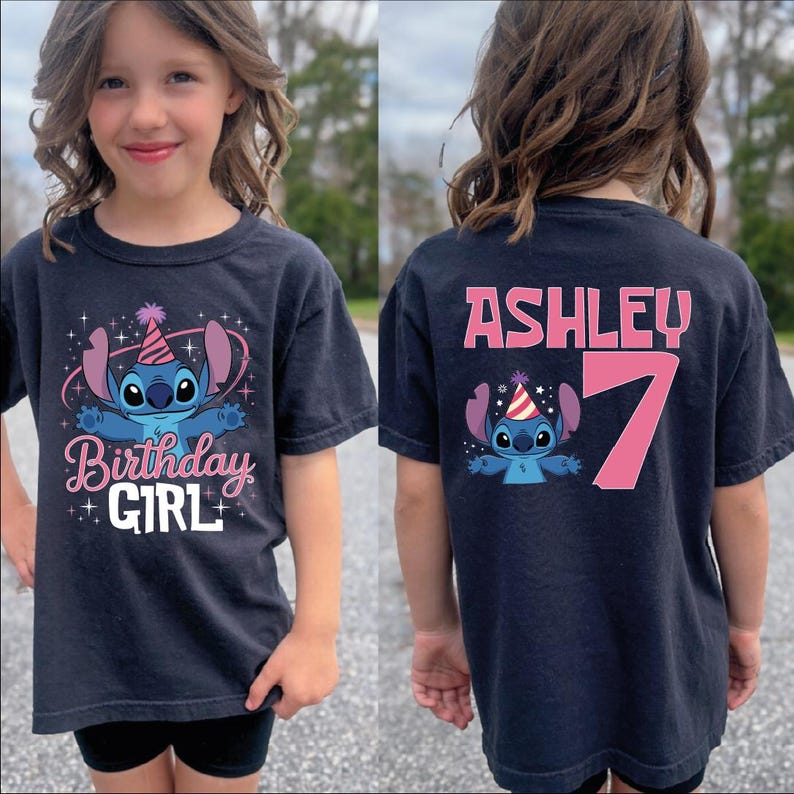 A young girl wearing a black t-shirt with a cartoon character and text printed on it.
