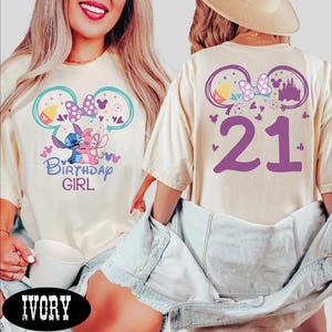 A woman wearing a white t-shirt with a birthday design and the number 21 on the back, along with a denim jacket.