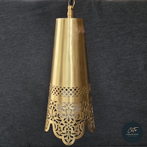 Könnte beinhalten: Eine goldene Pendelleuchte aus Metall mit einem konischen Schirm und filigranen Ausschnitten. Der Schirm hat einen gewellten unteren Rand.