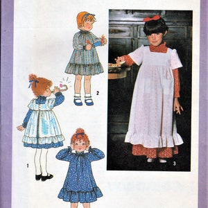 May include: Simplicity sewing pattern number 8812 for a child's dress. The pattern includes three different styles: a blue and white dress with a ruffle, a white dress with a ruffle, and a blue dress with a ruffle.