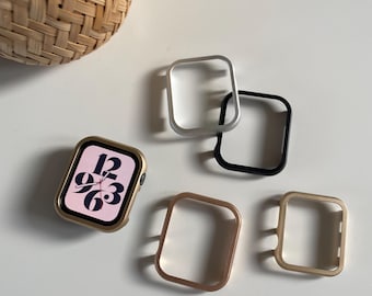 Può includere: Quattro custodie protettive di diversi colori per un Apple Watch. Le custodie sono argento, nero, oro e oro rosa. Il quadrante dell'orologio è visibile nell'immagine e mostra l'ora 12:36.