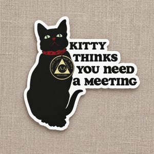 May include: A die-cut sticker featuring a black cat with green eyes wearing a red collar with a gold-coloured circular medallion. The medallion displays a triangle with the text AA, UNITY, SERVICE, and TO THINE OWN SELF BE TRUE. Text reads KITTY THINKS YOU NEED A MEETING.