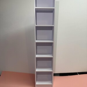 May include: White bookshelf with six shelves. The bookshelf is 1.6 inches wide.