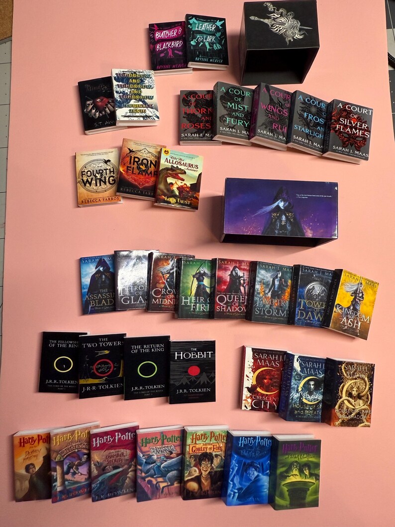 May include: A collection of miniature paperback books, including titles like "A Court of Mist and Fury", "The Hobbit", "Harry Potter and the Goblet of Fire", and "Iron Flame".