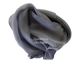 May include: A gray chiffon scarf, folded and arranged in a loose knot. The text "Neutral Gray On Chiffon" is printed on the scarf.