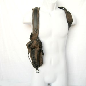 May include: A brown leather shoulder bag with a black strap and zipper. The bag has a small pocket on the front and is worn on a mannequin.