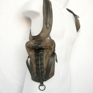 May include: A brown leather shoulder bag with black accents and a metal ring. The bag has a flap closure and a strap that goes over the shoulder.