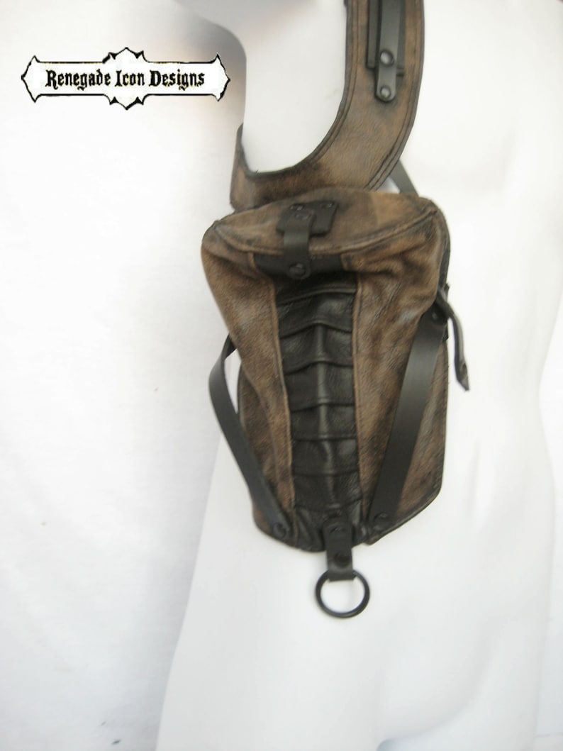 May include: A brown leather shoulder bag with black accents and a metal ring. The bag has a flap closure and a strap that goes over the shoulder.
