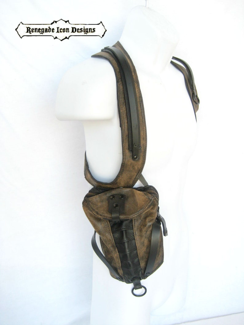 May include: A brown leather shoulder bag with black accents and a metal ring. The bag is worn on a mannequin's shoulder.