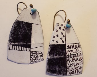 May include: A pair of black and white geometric patterned earrings with turquoise beads. The earrings are made of metal and have a hand-painted design. The earrings are about 2 inches long.