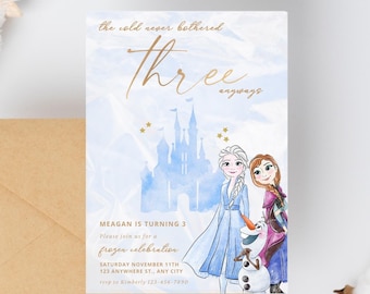 Puede incluir: Una tarjeta de invitación azul y blanca con un fondo de acuarela que presenta una silueta de un castillo y dos chicas de la película Frozen. El texto en la tarjeta dice "the cold never bothered three anyways" y "Meagan cumple 3 años. Únase a nosotros para una celebración congelada. Sábado 11 de noviembre. 123 Anywhere St., Any City. RSVP a Kimberly 123-456-7890."