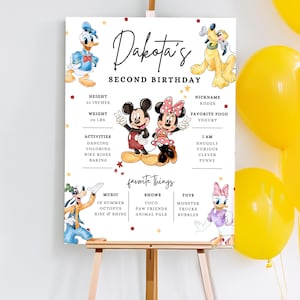 Könnte beinhalten: Ein personalisiertes Geburtstagsplakat auf einer Staffelei mit Micky und Minnie Maus. Das Schild enthält den Namen "Dakota's" und "Second Birthday", sowie Größe, Gewicht, Aktivitäten, Lieblingsdinge und andere Details. Gelbe Luftballons sind im Hintergrund.