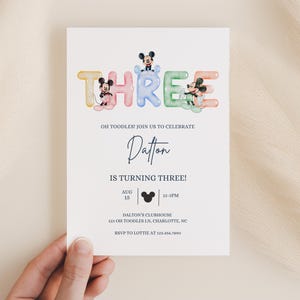 Puede incluir: Una invitación de cumpleaños con una ilustración colorida de personajes de Mickey Mouse que forman la palabra "TRES". La invitación es para la fiesta de cumpleaños número tres de un niño llamado Dalton. La fiesta se llevará a cabo en Dalton's Clubhouse el 15 de agosto de 12 a 4 PM.