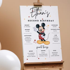 Könnte beinhalten: Ein weißes, bedruckbares Schild mit goldenen und roten Konfetti. Das Schild zeigt eine Comic-Illustration von Mickey Mouse und den Text "Ethan's Second Birthday". Das Schild enthält auch Informationen über Ethans Größe, Gewicht, Aktivitäten, Lieblingsdinge und Persönlichkeitsmerkmale.