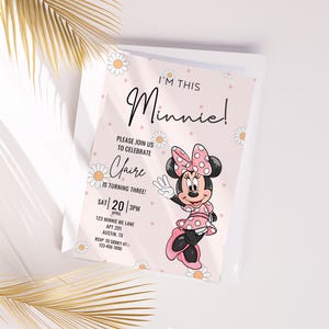 Puede incluir: Una invitación de cumpleaños con el tema de Minnie Mouse. La invitación es rosa y presenta el texto "I'M THIS Minnie!" y "Please join us to celebrate Claire is turning three!" con la fecha, hora y dirección. También aparece Minnie Mouse.