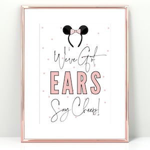May include: A printable sign with pink polka dots and black text that reads "We've Got Ears Say Cheesy!"  The sign features a black and pink Mickey Mouse ears headband.