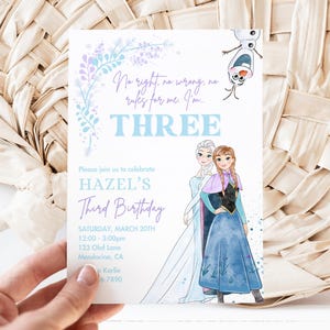 May include: Frozen themed birthday invitation with a blue and purple floral design. The invitation says "No right, no wrong, no rules for me I'm THREE." It also includes the text "Please join us to celebrate HAZEL'S Third Birthday" and details for the party.