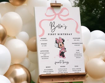 May include: A pink and white sign with a pink bow and the text "Bella's First Birthday". The sign includes details about the birthday girl, including her height, weight, activities, favourite things, and personality traits. A cartoon image of Minnie Mouse is featured on the sign.