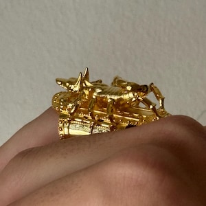 Puede incluir: Un anillo de tono dorado con un dise&ntilde;o de escorpi&oacute;n detallado. El escorpi&oacute;n est&aacute; encaramado sobre una base decorativa, creando una pieza de joyer&iacute;a &uacute;nica y llamativa.