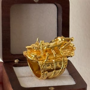 Puede incluir: Un anillo de oro con un dise&ntilde;o detallado de un escorpi&oacute;n. El anillo est&aacute; en una caja de madera.