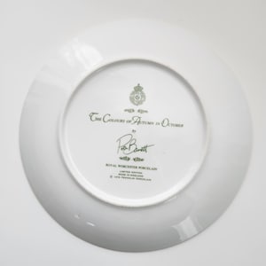 May include: White porcelain plate with the text "The Colours of Autumn in October" and the signature "Ron Barrett". The plate is a limited edition from Royal Worcester Porcelain, made in England.