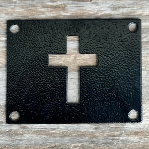May include: Black metal sign with a cut-out cross shape. The sign has four holes in the corners for hanging.