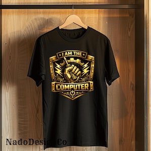 Può includere: T-shirt nero con grafica oro e nera. La grafica presenta una mano che tiene un cacciavite, fulmini e la scritta "I AM THE COMPUTER". Il design è incorniciato da uno scudo dorato.