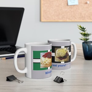 May include: Two white ceramic mugs with a gray background and a picture of a scone with jam and cream. The text on the mug reads "Which one will you eat yours?" and features a green and white checkered pattern.