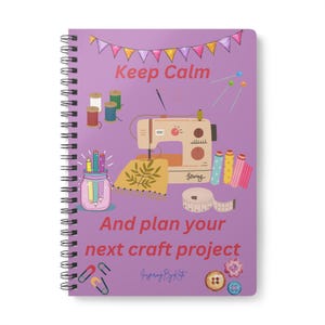May include: Purple notebook with a sewing machine, spools of thread, pencils, and buttons. The text on the cover reads "Keep Calm and plan your next craft project".
