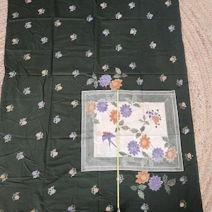 May include: Dark green fabric with a floral pattern. The fabric features small clusters of peach, purple, and white flowers scattered across the surface. A central square has a white background with a bird and floral design.