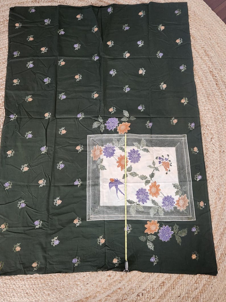 May include: Dark green fabric with a floral pattern. The fabric features small clusters of peach, purple, and white flowers scattered across the surface. A central square has a white background with a bird and floral design.