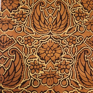 May include: Close-up of a fabric with a repeating pattern of stylized floral and leaf motifs in shades of brown and cream. The design features symmetrical arrangements with intricate details, creating a vintage or antique aesthetic.