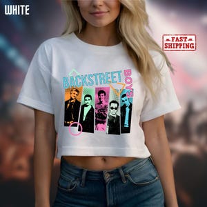 May include: White crop top featuring a colorful graphic of the Backstreet Boys. The design includes the band's name and individual portraits of the members in a retro style. The shirt has a crew neck and short sleeves.
