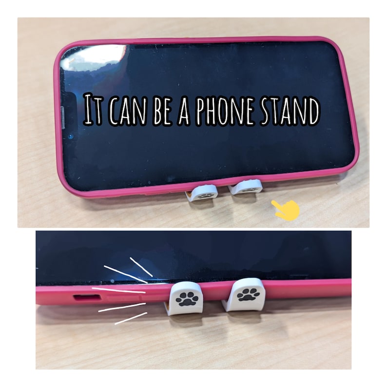May include: A pink phone case with white paw print phone stand attachments. The phone case is on a wooden surface. The text "IT CAN BE A PHONE STAND" is visible on the phone screen.