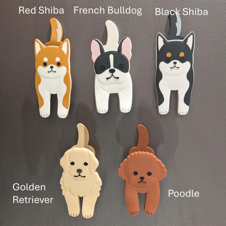 May include: Five different dog breed magnets, each with a different color and design. The magnets are shaped like the dogs, with their tails curled up. The dogs are a red Shiba Inu, a French Bulldog, a black Shiba Inu, a golden retriever, and a poodle.