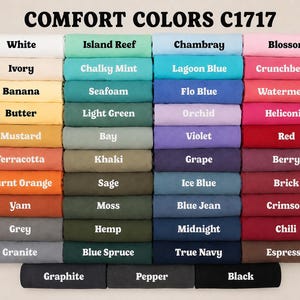 May include: A color chart for Comfort Colors C1717 t-shirts, displaying forty-four folded fabric swatches in various shades including white, ivory, yellow, orange, red, pink, purple, blue, green, grey, brown, and black, each labeled with its specific color name.