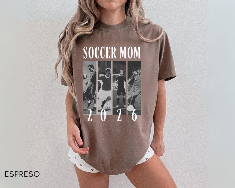 May include: Espresso-colored t-shirt with the text "SOCCER MOM 2026" in white. The shirt features a black and white collage of soccer players. The shirt is a short-sleeved, crew neck style.