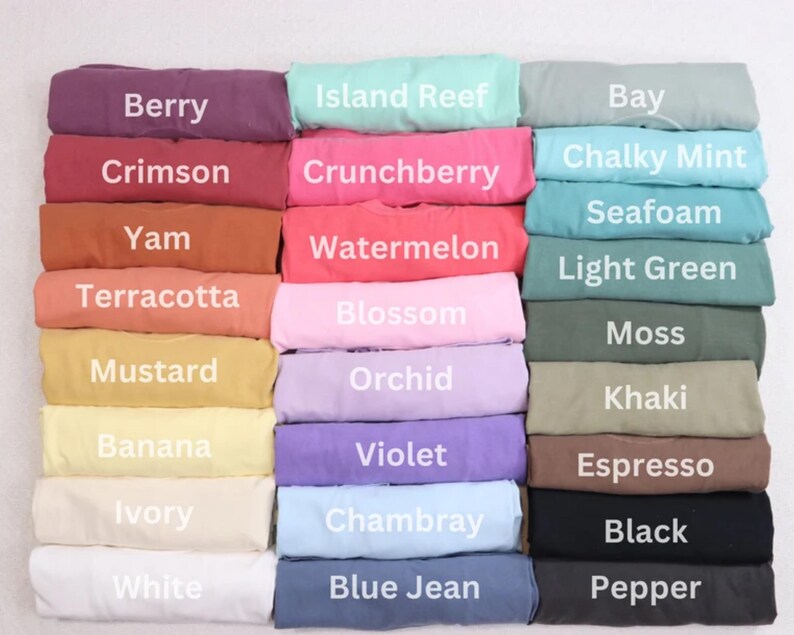 Op de afbeelding: Een display van gevouwen stof in verschillende kleuren, waaronder Berry, Crimson en Yam. Elke kleur is gelabeld met zijn naam in witte tekst. Andere kleuren zijn Island Reef, Crunchberry en Chalky Mint. De stof lijkt zacht.