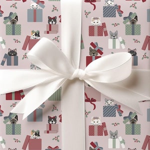 May include: Pink gift wrap with a repeating pattern of cats peeking out of gift boxes. The boxes are decorated with red, green, and blue stripes. A white ribbon is tied around the gift box.