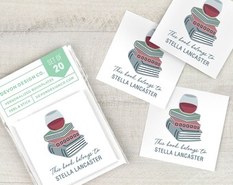 May include: Set of 20 personalized bookplates with a wine glass and stack of books design. The text on the bookplates reads "This book belongs to Stella Lancaster".